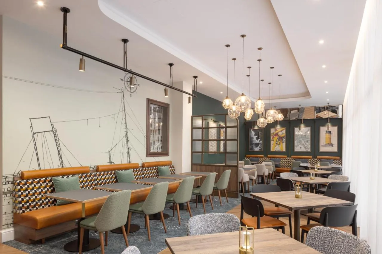 a restaurant with tables and chairs and chandeliers at Residence Inn by Marriott Belfast Titanic Quarter in Belfast