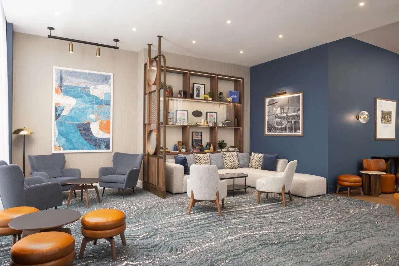 a living room with a couch and tables and chairs at Residence Inn by Marriott Belfast Titanic Quarter in Belfast